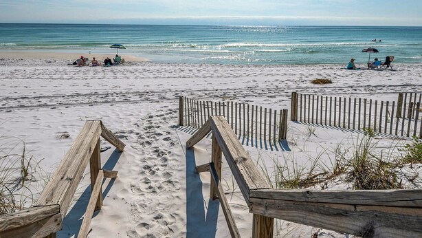 A sandy beach with wooden walkways and people relaxing under umbrellas. - Directly on the Gulf, Free Beach Chairs, Comfy Escape (Miramar Beach)