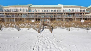 A multi-story beachfront hotel with balconies, a sandy beach in front, and a clear blue sky. - Directly on the Gulf, Free Beach Chairs, Comfy Escape (Miramar Beach)