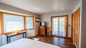 A bedroom with a bed, a dresser, a chair, a television, and a sliding glass door leading to a balcony.
