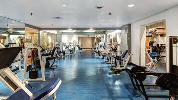 A gym with various exercise machines, a blue floor, and mirrors on the walls.