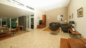 Ein geräumiges Wohnzimmer mit Kamin, modernen Möbeln und großen Fenstern.