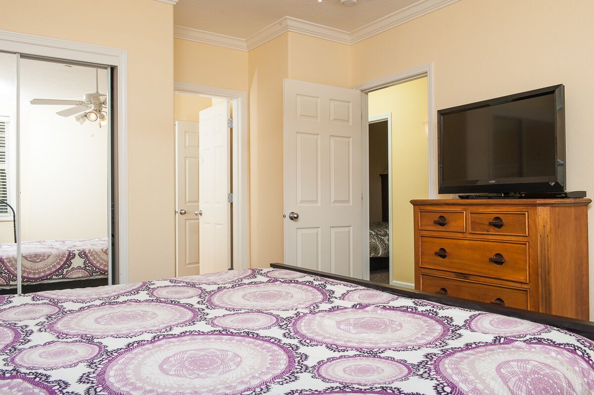 Un dormitorio con cama, cómoda, televisor y puerta.