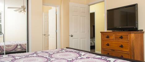 Un dormitorio con cama, cómoda, televisor y puerta.