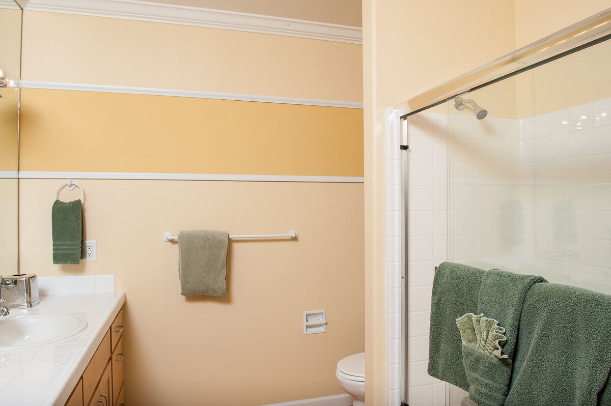 Une salle de bain équipée d’un lavabo, d’un miroir, d’un porte-serviettes et d’une cabine de douche en verre.