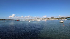 A marina with multiple boats docked, a clear sky, and a distant shoreline with buildings. - Royal William Yard Apartment (Plymouth)