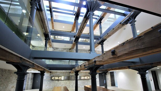 A spacious atrium with high ceilings, exposed beams, and a central wooden table. - Royal William Yard Apartment (Plymouth)