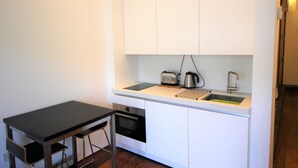 A compact kitchenette with a black countertop, a built-in oven, a sink, and a toaster. - Royal William Yard Apartment (Plymouth)