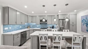 A modern kitchen with grey cabinets, a white island, and pendant lighting. - Newly Renovated Waterfront Dock View 2 bed, 2 bath at Sanibel Moorings #1431 (Sanibel)