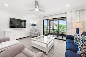 A modern living room with a flat-screen TV, a ceiling fan, a glass coffee table, and a sofa. - Newly Renovated Waterfront Dock View 2 bed, 2 bath at Sanibel Moorings #1431 (Sanibel)
