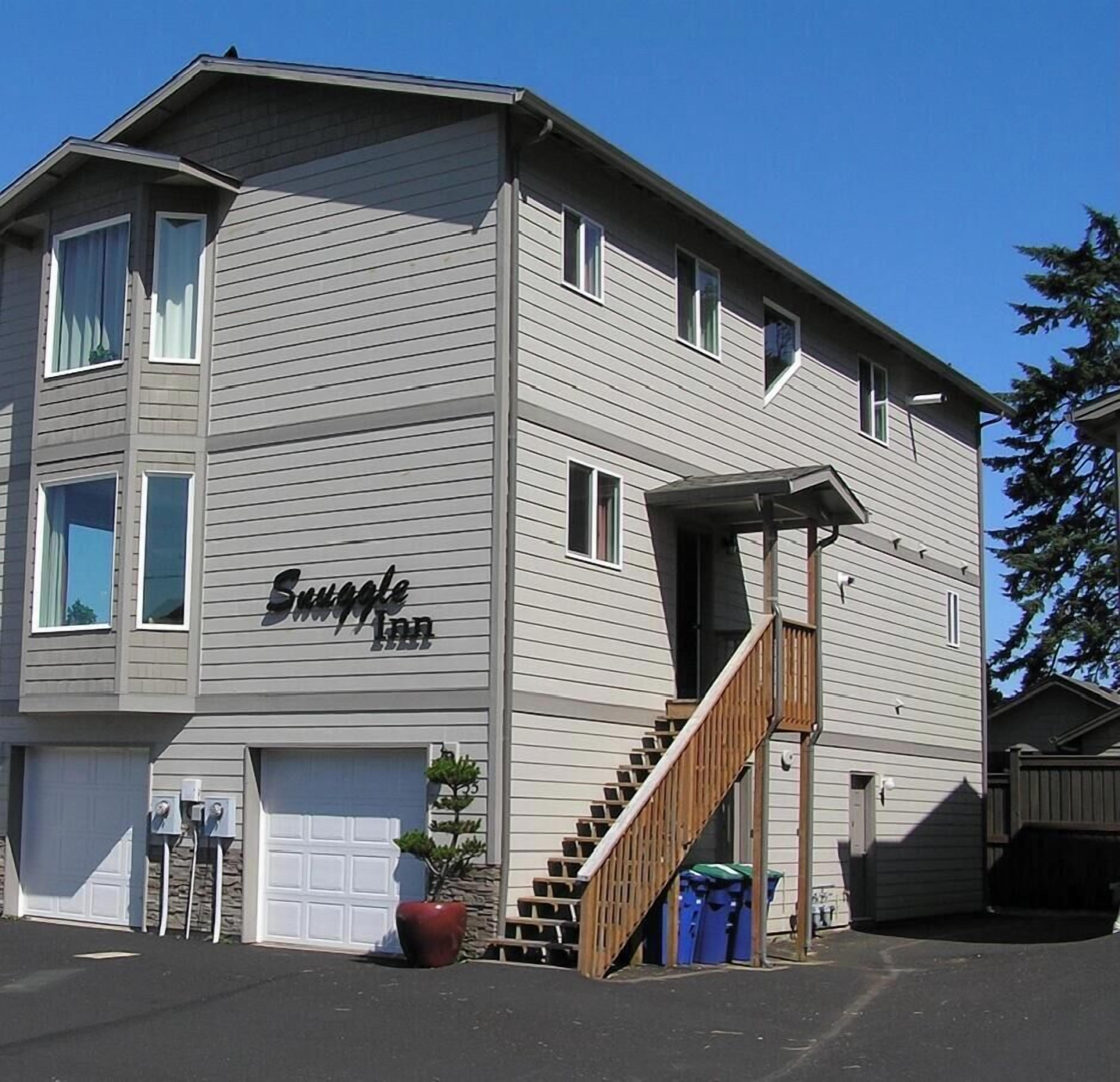 A two-story building with a sign reading "Snuggle Inn." There is a staircase leading to the second floor, and a garage door is visible on the ground floor.