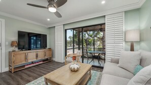A living room with a television, wooden cabinet, and a ceiling fan.