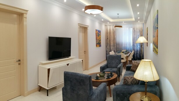 Ein modernes Wohnzimmer mit Flachbildfernseher, bequemen Sitzgelegenheiten und einem Essbereich mit Tisch und Stühlen.