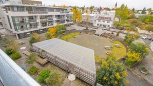 Un edificio moderno con varios pisos, un patio con asientos y abundante vegetación.