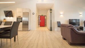 Un apartamento moderno con comedor, kitchenette, sala de estar y una puerta roja.