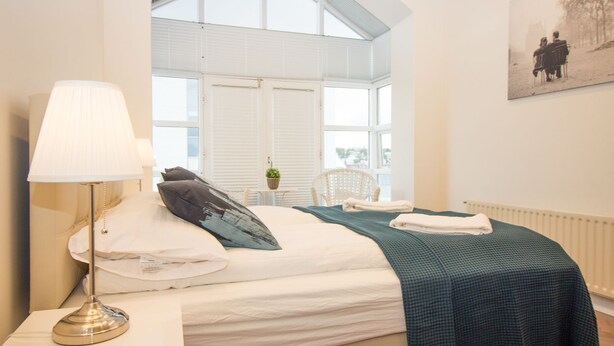 Un dormitorio con cama, lámpara, silla y ventana.