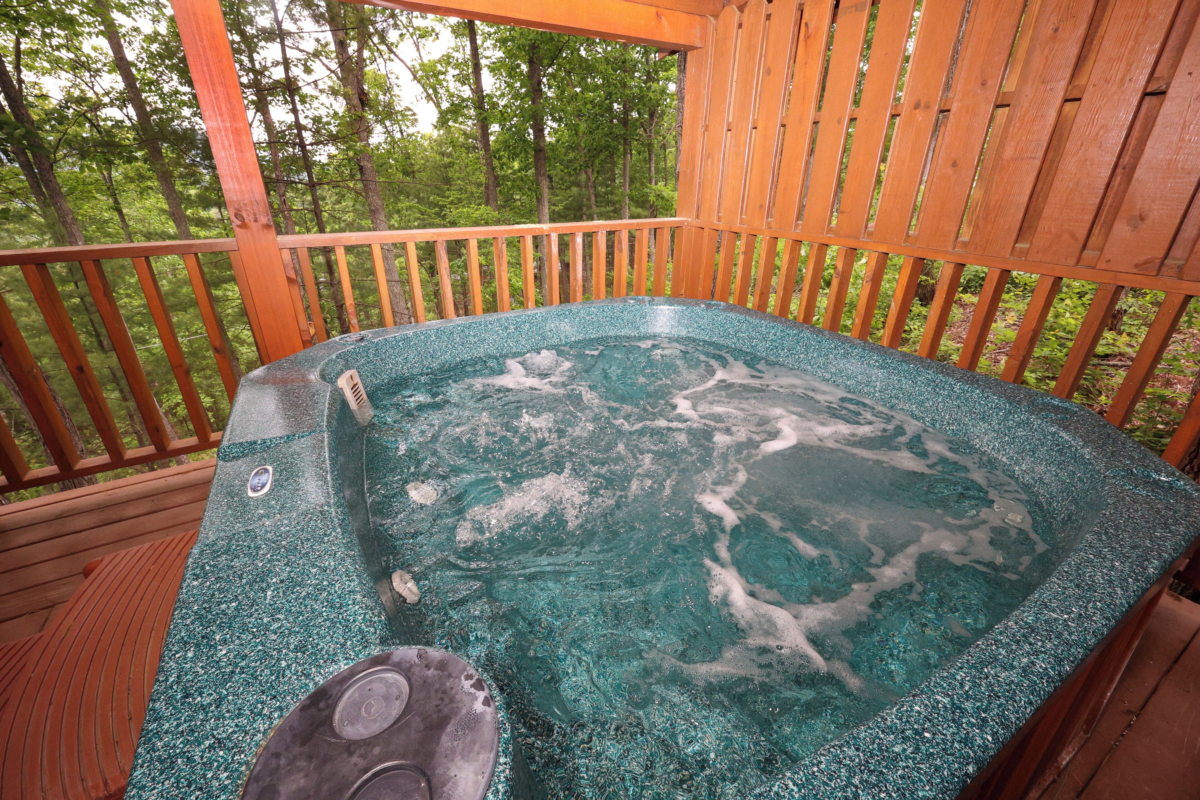 A hot tub on a wooden deck with a view of a forest.