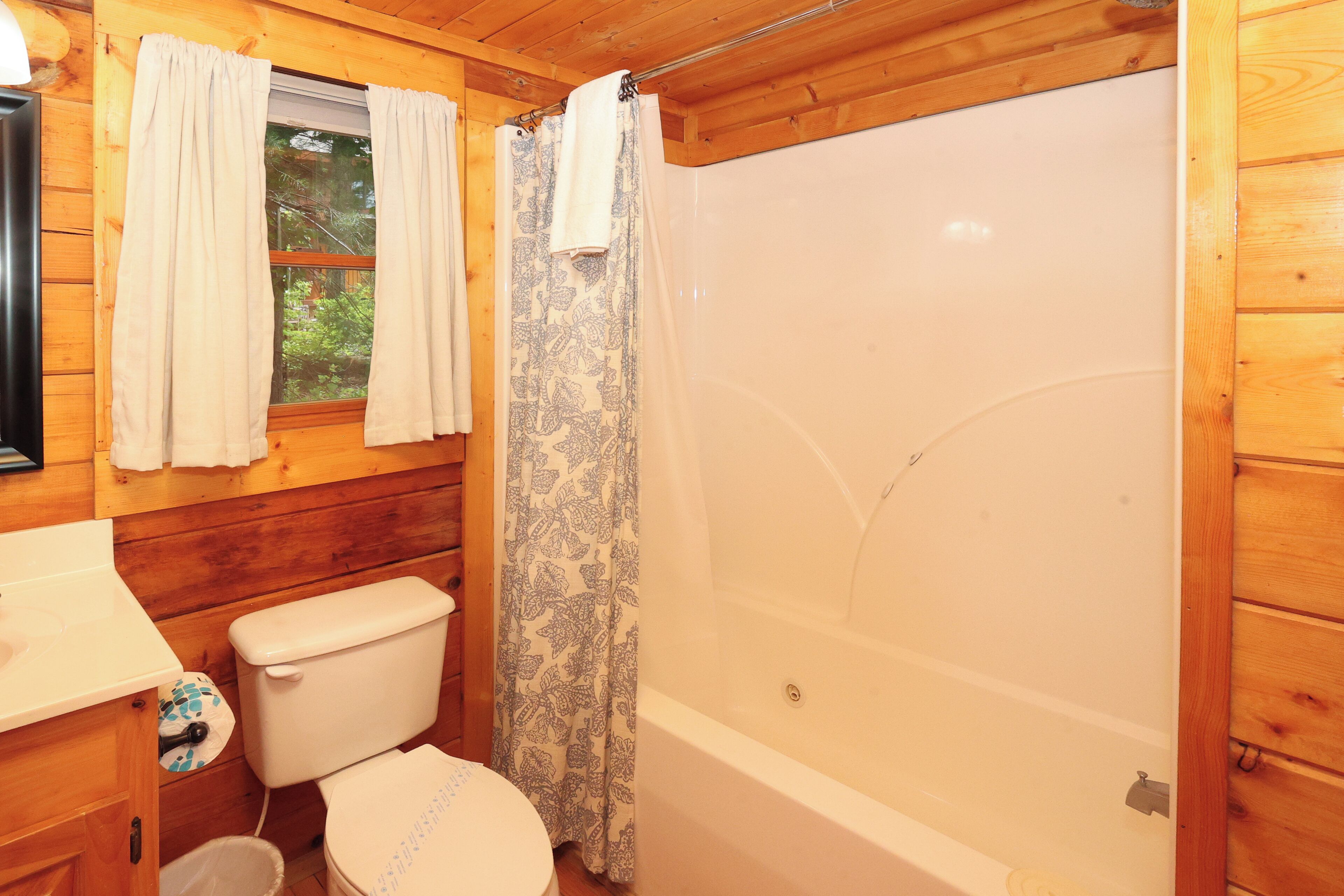 A wooden cabin bathroom with a toilet, sink, and shower.