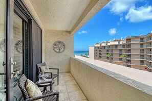 A balcony with wicker furniture and a view of the ocean and buildings. - Best location on Siesta Key/Crescent Beach - just steps to the water! (Sarasota)