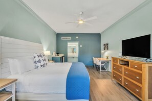 A hotel room with a bed, a desk, a television, and a dresser.