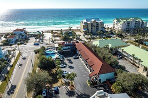 A coastal hotel with multiple buildings, a parking lot, and a view of the ocean.