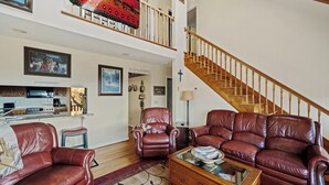 A spacious living room with leather sofas, a wooden coffee table, and a staircase. - Mountain Cabin,Panoramic View,Hot Tub, WiFi, Fire Table (Ferguson)