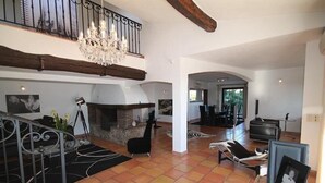 A spacious living area with a fireplace, lounge chairs, and a chandelier. - Large sea-view villa with 3 independent apartments (Mandelieu-la-Napoule)