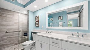 A modern bathroom with a shower, toilet, and two sinks.