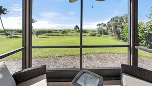 A covered outdoor seating area with a view of a grassy field and trees.