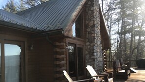 A log cabin with a stone chimney, wooden deck, and outdoor seating. - Mountain Cabin,Pet-Friendly,Views,HotTub,Deck,WiFi (Ferguson)