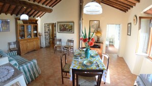 A dining area with a table set for four, surrounded by chairs, in a room with exposed wooden beams and a tiled floor. - Home on the hills overlooking Pescia, between Lucca and Florence, private pool with salted water (Lanciole)