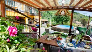 A covered outdoor dining area with a pool, surrounded by lush greenery and a view of a village. - Home on the hills overlooking Pescia, between Lucca and Florence, private pool with salted water (Lanciole)