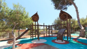 Un parque infantil con una estructura de madera para escalar, toboganes y marcas de colores en el suelo.