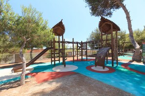 A playground with a wooden climbing structure, slides, and colorful ground markings.