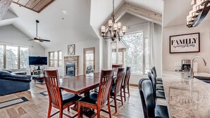 A spacious living area with a large wooden dining table, comfortable seating, a fireplace, and a television.