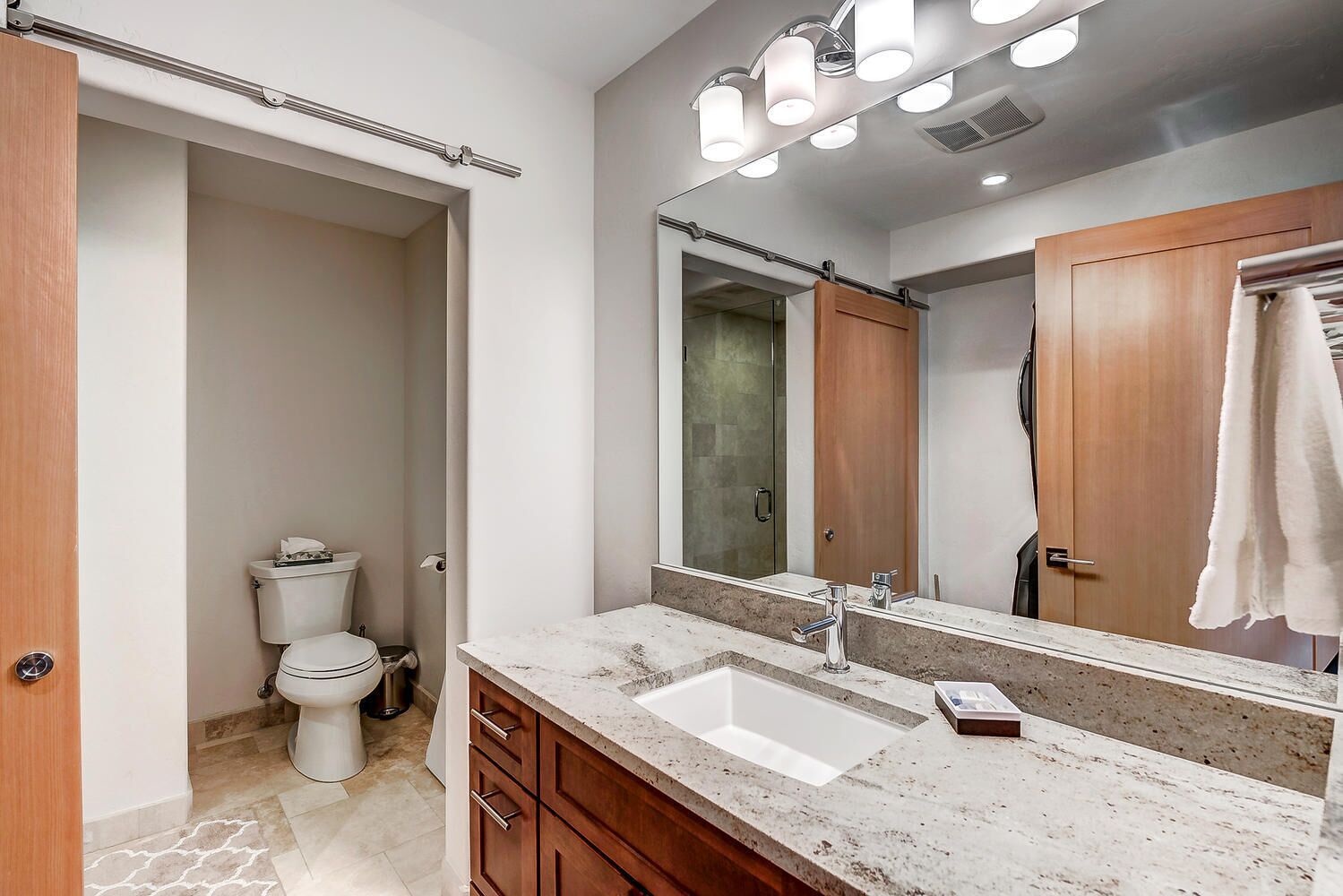 Une salle de bain avec un lavabo blanc, un meuble-lavabo en bois et un grand miroir.