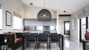 A modern kitchen with a central island, black chairs, and a hanging light fixture.