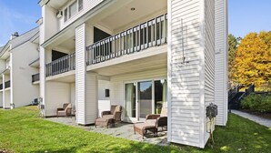 A two-story building with a covered patio area featuring outdoor furniture. - Ski-in/Ski-out Lodge Condo at Toll House Lift (Stowe)