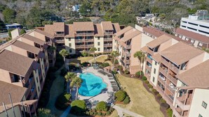 A multi-story hotel with a central courtyard featuring a swimming pool, surrounded by balconies and lush landscaping. - Oceanfront view park on ocean nearby for kids (MYRTLE BEACH)