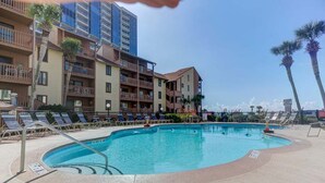 A pool area with lounge chairs, a pool, and multi-story buildings with balconies. - Oceanfront view park on ocean nearby for kids (MYRTLE BEACH)