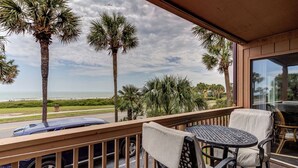 A balcony with a view of the beach, palm trees, and a car parked outside. - Oceanfront view park on ocean nearby for kids (MYRTLE BEACH)