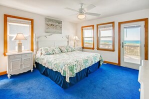 A bedroom with a bed, a ceiling fan, and a view of the beach through the windows. - Oceanfront Dog Friendly Home in Hatteras w/ Pool, Hot Tub, Elevator, Game Room (Hatteras)