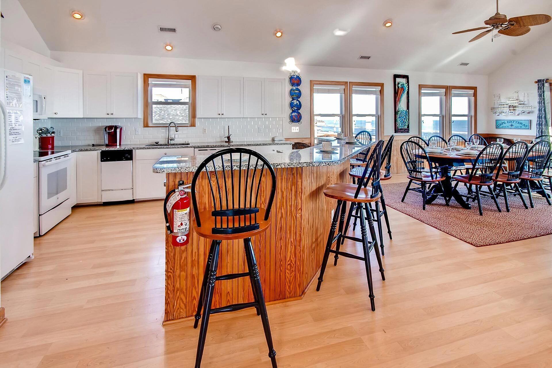 A modern kitchen with white cabinets, a wooden island, and a dining area with black chairs and a wooden table.