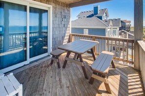 A wooden deck with a table and benches, overlooking a residential area with houses and a clear sky. - Oceanfront Dog Friendly Home in Hatteras w/ Pool, Hot Tub, Elevator, Game Room (Hatteras)