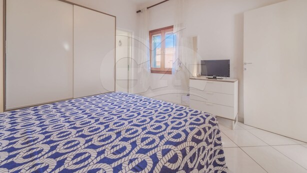 A bedroom with a bed, a TV, and a wardrobe.