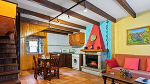 A kitchen with wooden cabinets, a dining table with chairs, a washing machine, and a fireplace.