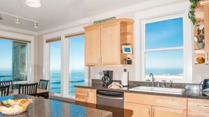 Una cucina con mobili in legno, lavastoviglie e vista sull'oceano.