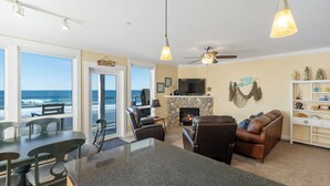 Een ruime woonkamer met een groot eiland, comfortabele zithoek, een open haard en uitzicht op de oceaan.