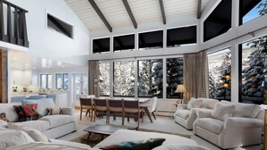 A spacious living room with a high ceiling, large windows, and a view of snow-covered trees. - Vail Village + Private Hot Tub, Game Room & Prestigious Forest Road Location (Vail)
