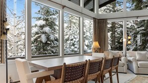 A modern interior with a large dining table, wooden chairs, and a sofa. - Vail Village + Private Hot Tub, Game Room & Prestigious Forest Road Location (Vail)