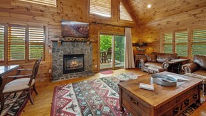 A cozy cabin interior with a stone fireplace, leather furniture, and a large rug. - Brook Haven: Private Cabin, Great Views, Hot Tub, WiFi, Fireplace (Ferguson)